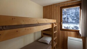 Habitación con literas y vista a un bosque nevado.