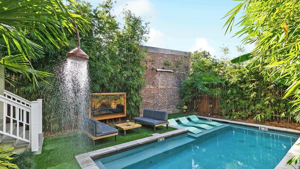Un patio trasero con piscina, fuente de agua y mobiliario para exteriores.