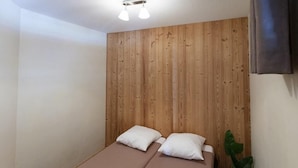 A small room with two single beds, a wooden headboard, a potted plant, and a ceiling light fixture. - 50m from ski slopes, 3rd floor, balcony, tv, ski locker, 38m², Serre Chevalier (Briançon)