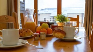 Et morgenbord med croissanter, en skål med frugt, en kande og en kop kaffe.