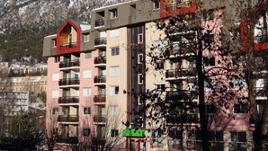 Un hotel de varios pisos con balcones y montañas al fondo.