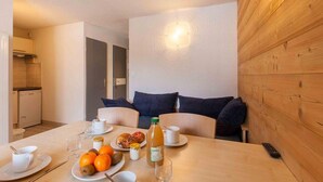 Un comedor con una mesa preparada para el desayuno, que incluye frutas, bollería y bebidas.