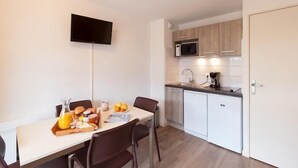 Una cocina compacta con microondas, lavabo y televisor de pantalla plana montado en la pared.