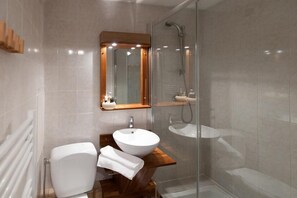 Features a large vessel sink, separate sink, and glass-enclosed shower area with handheld showerhead.