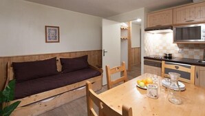 Une cuisine compacte avec des meubles en bois, un four à micro-ondes et une table à manger agrémentée d’assiettes et de verres.