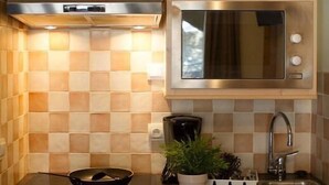 Une cuisine de taille réduite, dotée de meubles en bois, d’un four à micro-ondes, d’un évier et d’un lave-vaisselle.