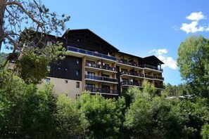 Ein mehrstöckiges Hotel mit Balkonen, umgeben von Bäumen.
