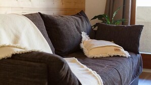 A dark brown sofa with multiple cushions, including a white one with a label. - 50m from ski slopes, 6th floor, balcony, tv, ski locker, 24m², Serre Chevalier (Briançon)