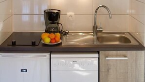 A compact kitchen with wooden cabinets, a microwave, a coffee maker, and a dishwasher. - 200m from resort center, 3rd floor, balcony, tv, ski locker, 25m², Serre Chevalier (Briançon)