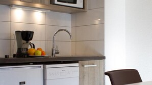 A compact kitchen with wooden cabinets, a microwave, a coffee maker, and a dishwasher. - 200m from resort center, 3rd floor, balcony, tv, ski locker, 25m², Serre Chevalier (Briançon)