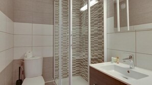 Een moderne badkamer met een douchecabine van glas, een wit toilet en een wastafel met spiegel.
