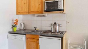 Une cuisine de taille réduite, dotée de meubles en bois, d’un four à micro-ondes, d’une cuisinière et d’un lave-vaisselle.