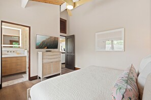 Une chambre à coucher avec un lit, une commode, un téléviseur et une fenêtre.