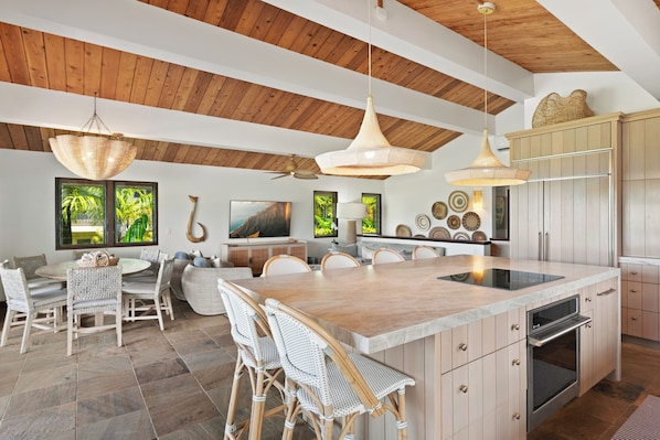 Una cocina amplia con una isla grande, techo de madera e iluminación colgante moderna.