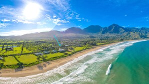 An aerial view of a coastal area with a beach, ocean, and mountains in the background.