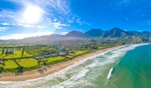 An aerial view of a coastal area with a beach, ocean, and mountains in the background.