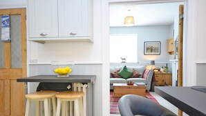 A modern kitchen with white cabinets, a black countertop, and two wooden stools.