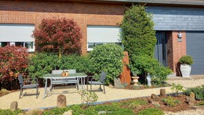 A two-story house with a tiled roof, brick walls, and a garage door. - Apartment in a quiet location, in the middle of orchards on the outskirts of St.Tönis (Tönisvorst)
