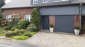 A two-story house with a dark grey roof, a brick facade, and a number '158' on the door. - Apartment in a quiet location, in the middle of orchards on the outskirts of St.Tönis (Tönisvorst)