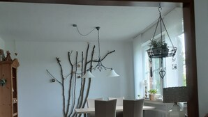 A dining area with a table and chairs, a hanging light fixture, and a brick fireplace. - Apartment in a quiet location, in the middle of orchards on the outskirts of St.Tönis (Tönisvorst)