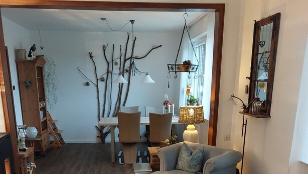 A cozy living room with a wooden floor, a sofa, a coffee table, and a dining area with chairs. - Apartment in a quiet location, in the middle of orchards on the outskirts of St.Tönis (Tönisvorst)