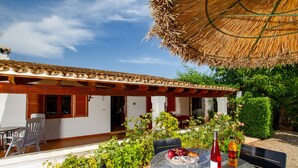 A patio with a round table, chairs, a bottle of red wine, and a bottle of orange juice.