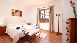 A bedroom with a bed, bedside tables, a wooden dresser, a window with curtains, and a painting on the wall. - L´Embat ( Tolo ) Charming 2 bedroom villa (Pollensa)