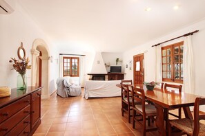 A dining area with a wooden table and chairs, a fireplace, and a television. - L´Embat ( Tolo ) Charming 2 bedroom villa (Pollensa)
