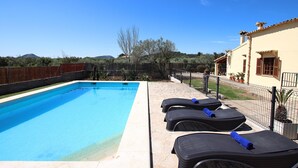 A swimming pool with lounge chairs, a stone patio, and a fenced yard with a view of hills. - L´Embat ( Tolo ) Charming 2 bedroom villa (Pollensa)