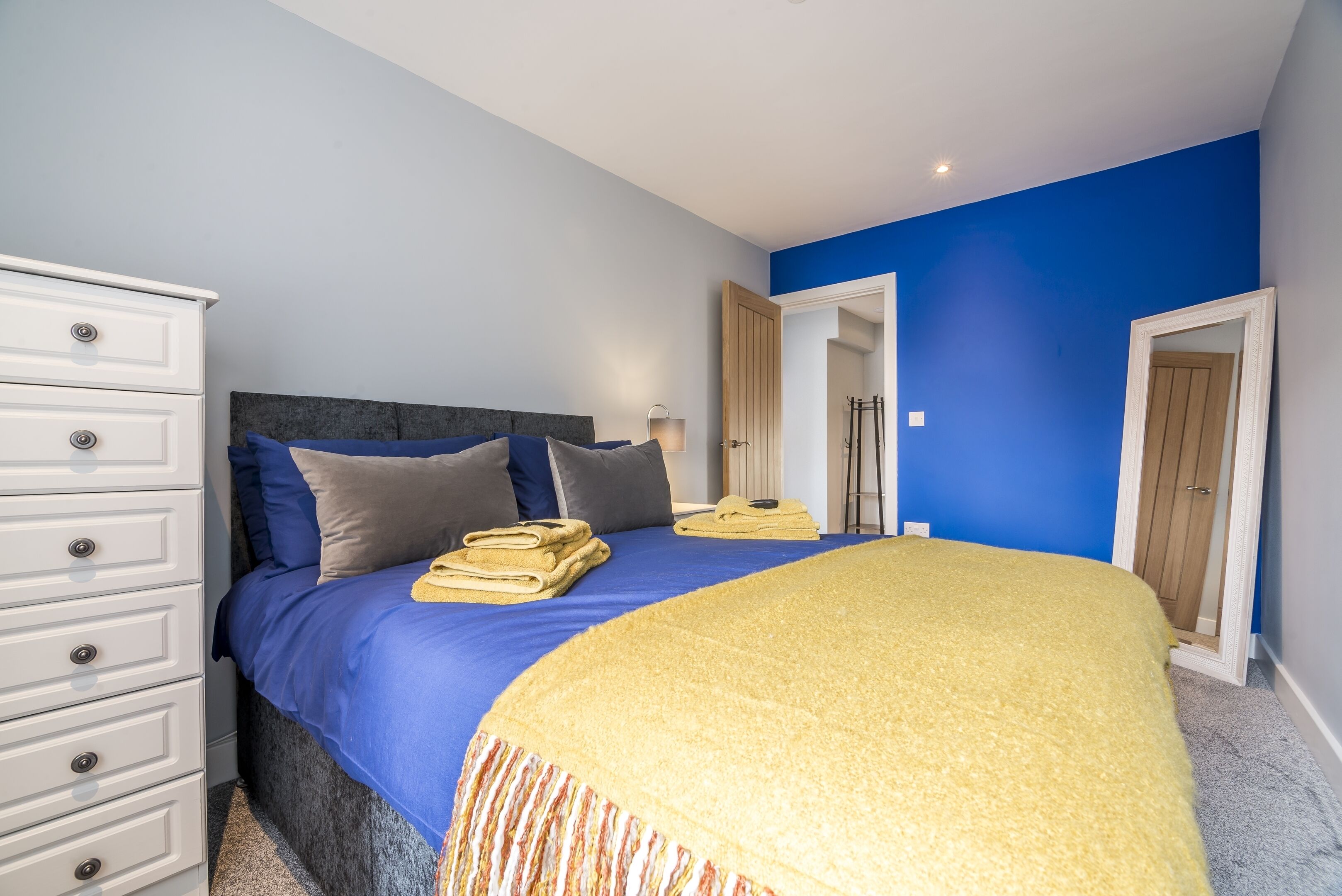 Una camera da letto con un letto, una cassettiera bianca e una parete blu.