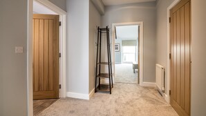 Un couloir avec des portes en bois, un porte-manteau et un sol recouvert de moquette.