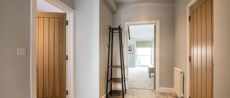 A hallway with wooden doors, a coat rack, and a carpeted floor.