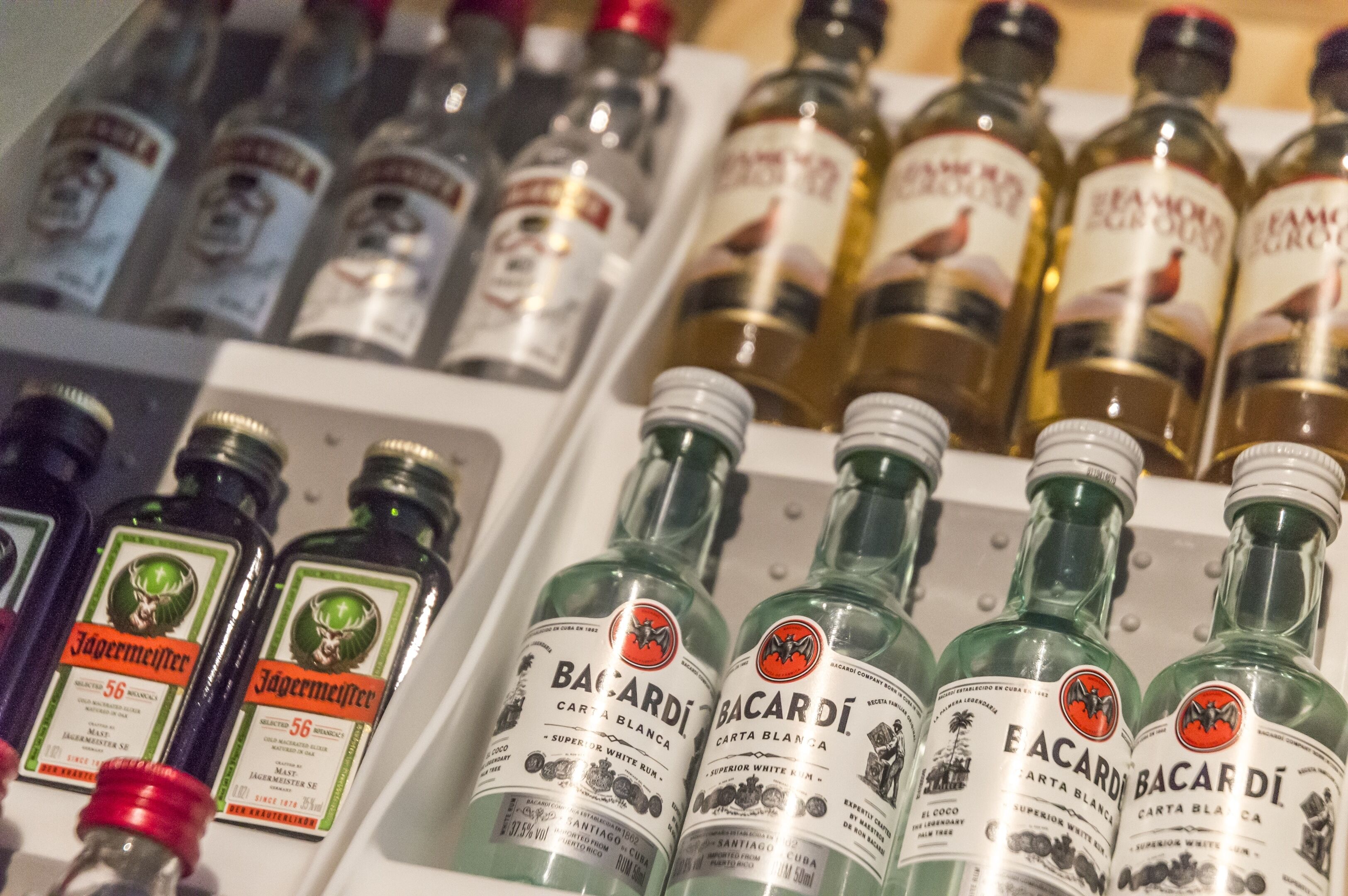 Une variété de bouteilles de spiritueux, dont des bouteilles de Bacardi et de Jägermeister, sont exposées sur des étagères.