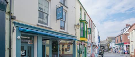 A street with buildings, including a pub with a blue awning and a sign that reads "The Olde House."