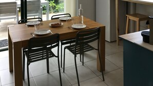 Ruokailutila, jossa on puinen pöytä, mustat tuolit ja katosta roikkuva valaisin.