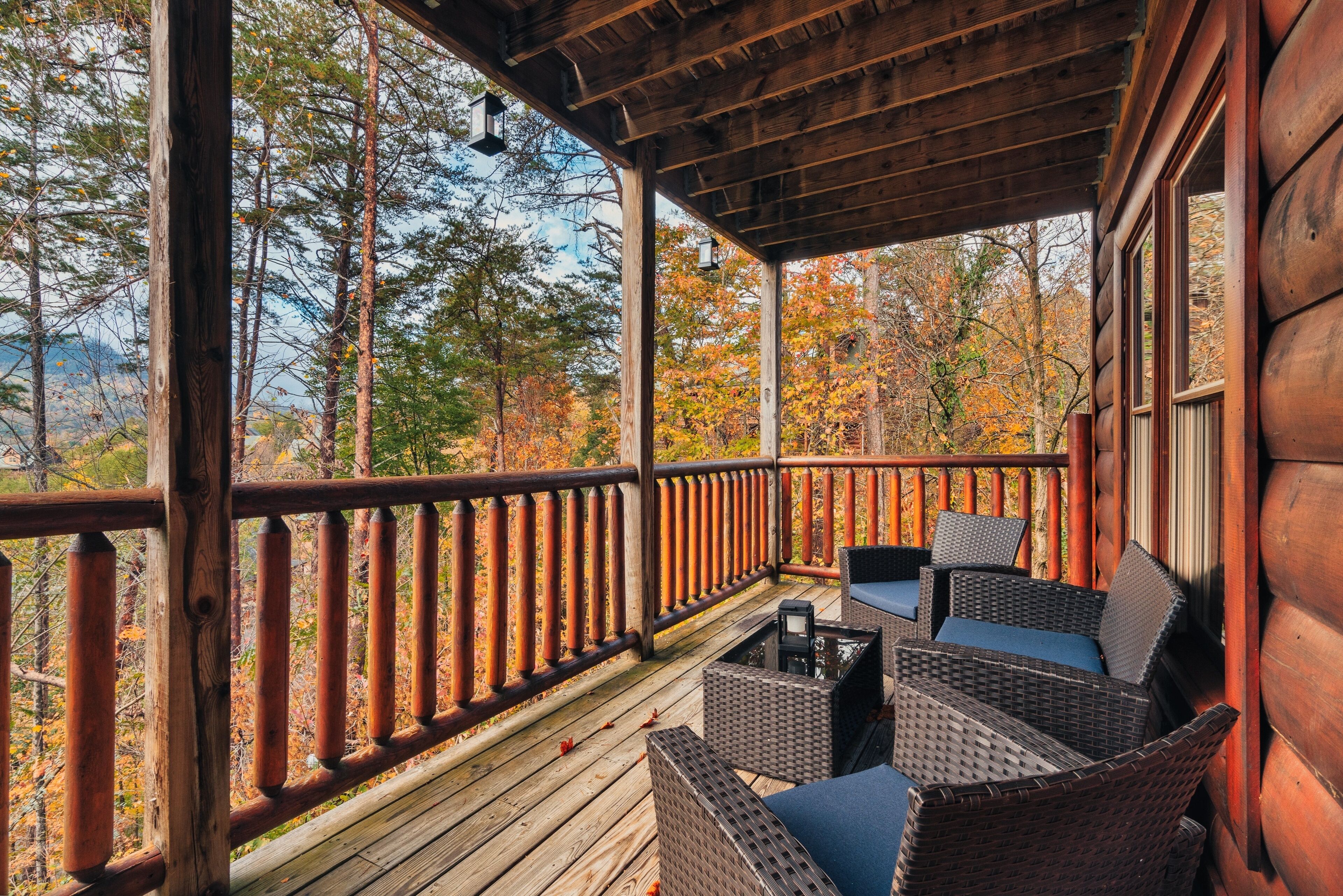 A wooden deck with wicker furniture and a view of autumn trees.