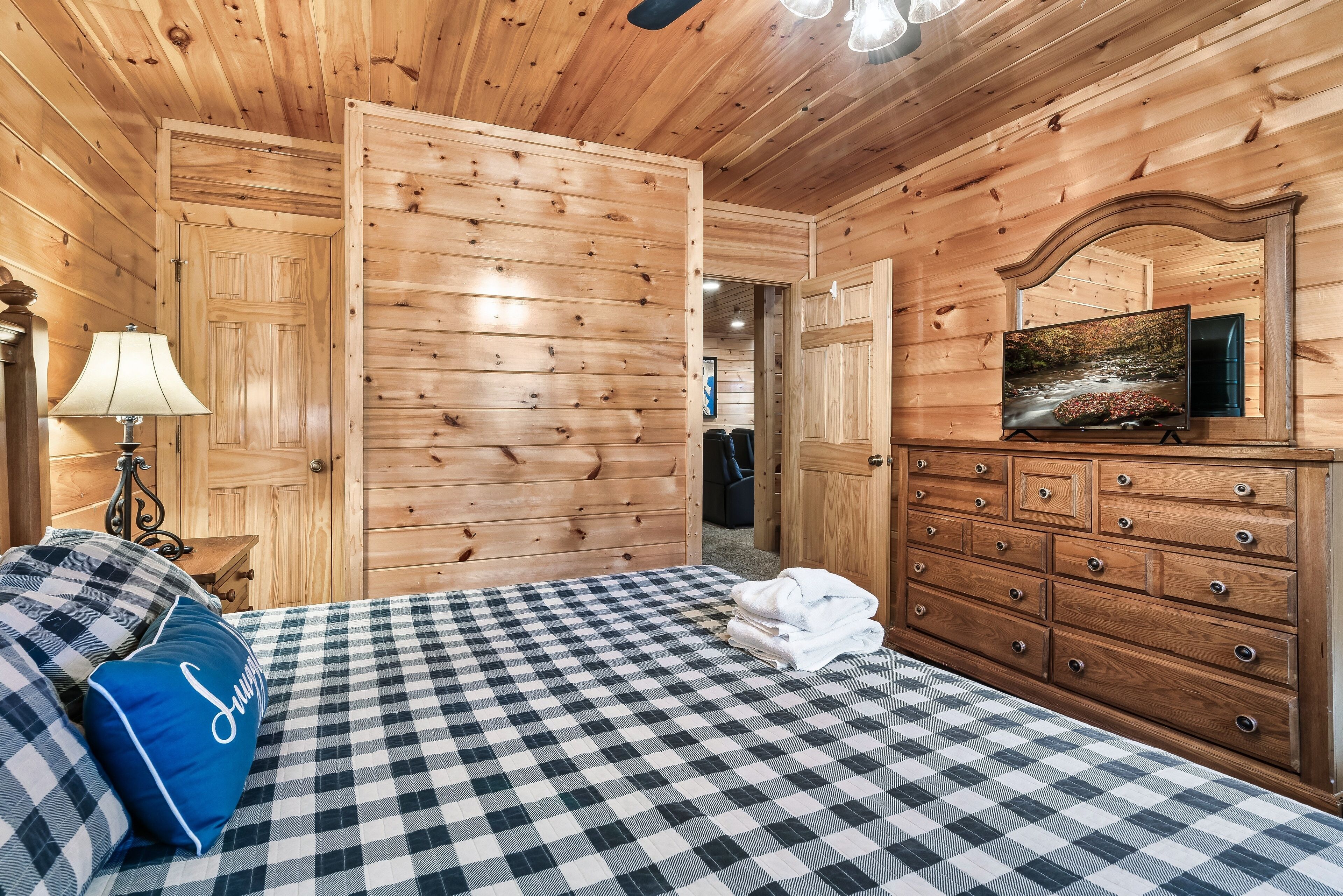 Una habitación con paneles de madera, una cama, un aparador y un televisor.
