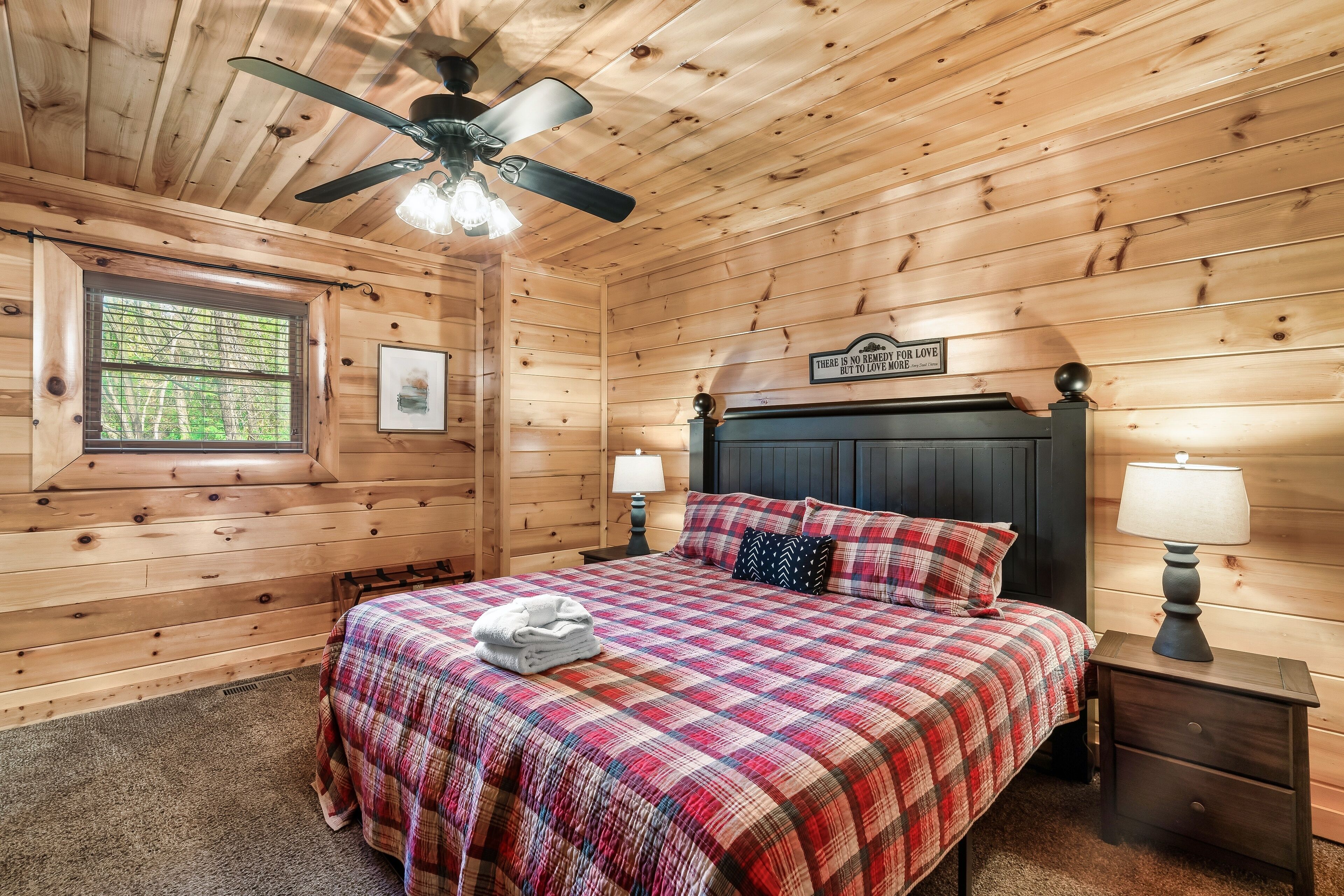 Ein Schlafzimmer einer Holzhütte mit Bett, Deckenventilator, Fenster und einem Schild an der Wand.