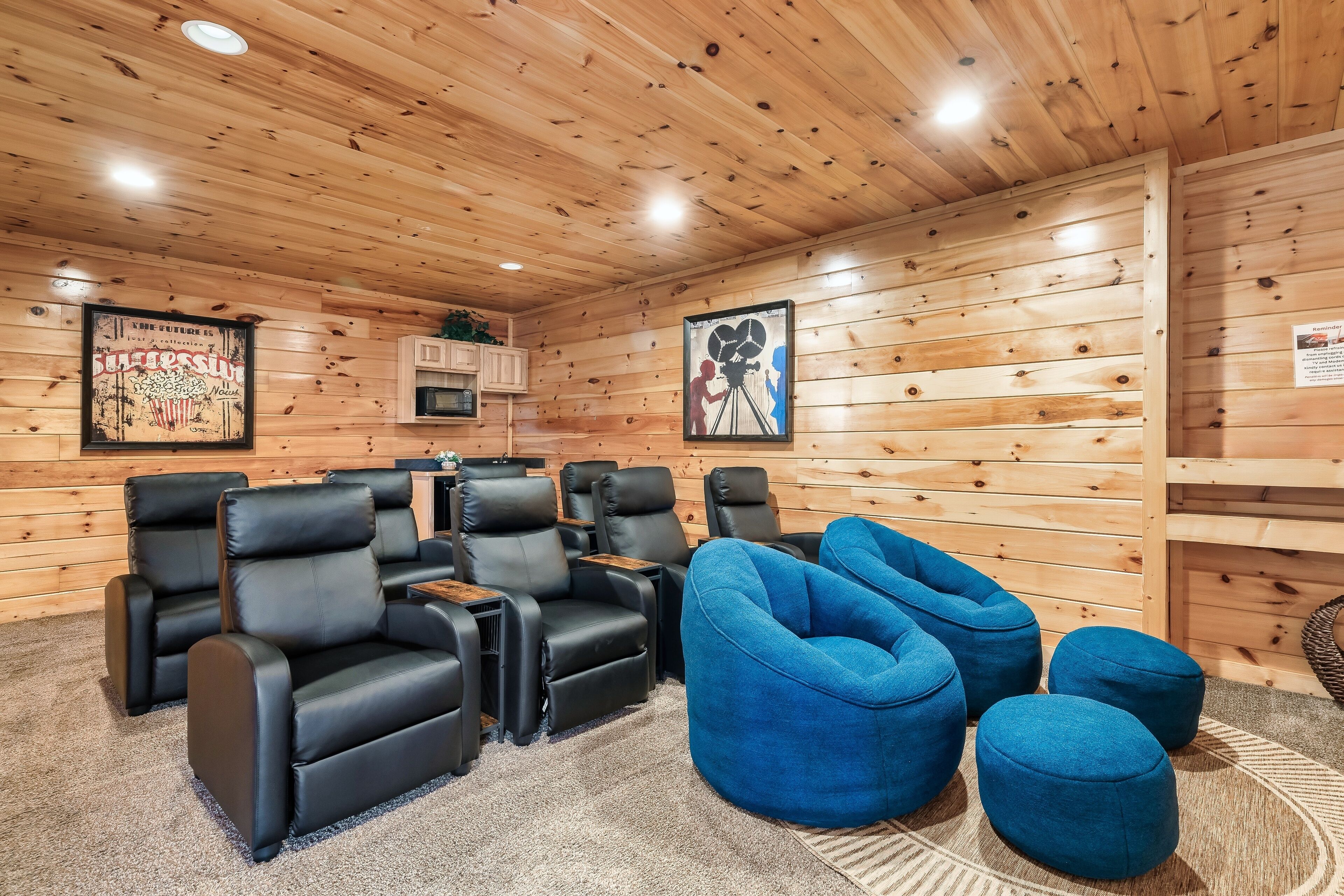 A cozy room with wooden walls, black leather recliners, and blue bean bag chairs.