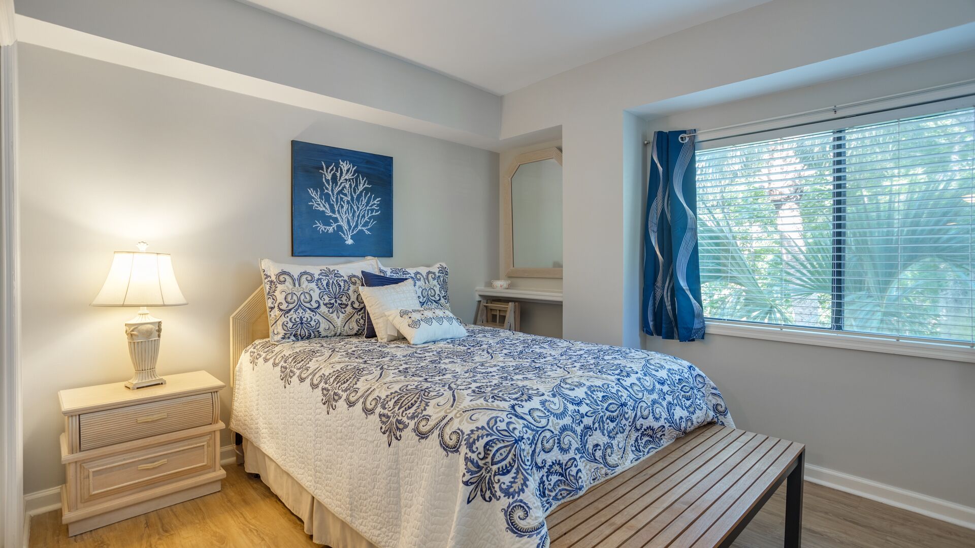 A bedroom with a bed, bedside table, lamp, and a window with curtains.