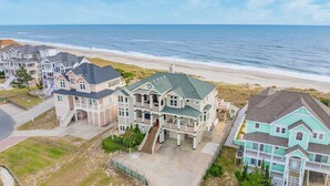 A coastal residential area with houses featuring multiple stories, balconies, and a beach view. - Premier Oceanfront Dog Friendly w/ Pool, Elevator, Hot Tub, Theater, Game Room (Hatteras)