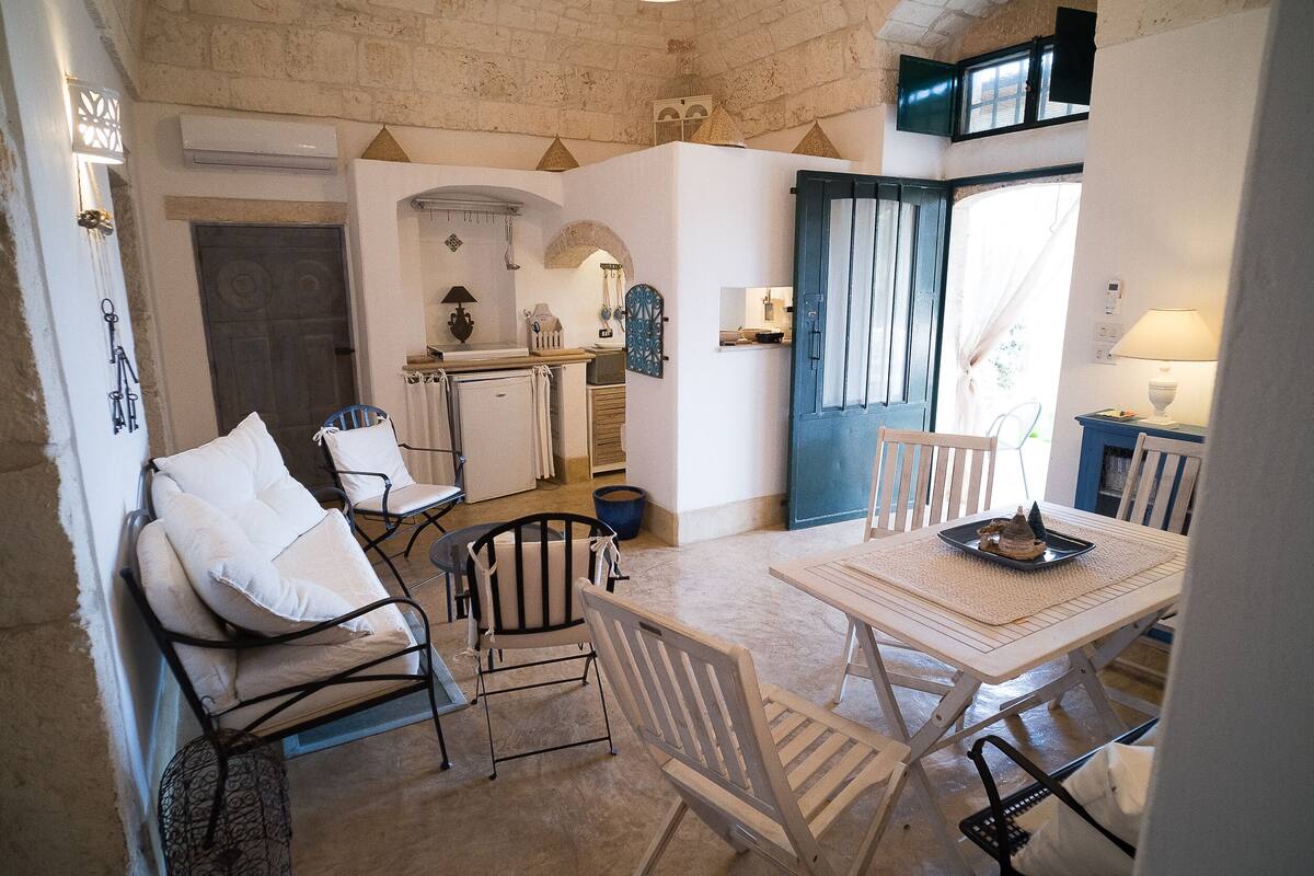 Un comedor acogedor con una mesa y sillas, una cocina al fondo y una puerta que da al exterior.