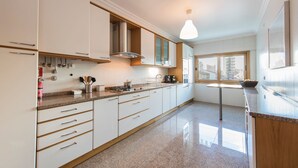 Una cocina moderna con armarios blancos, encimeras de granito y una estufa empotrada.