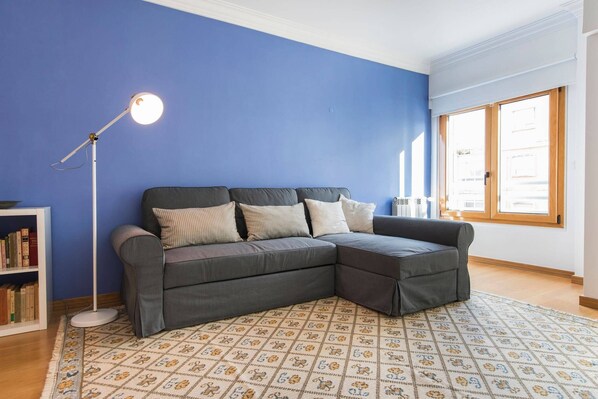 A modern living room with a sectional sofa, a floor lamp, and a patterned rug.