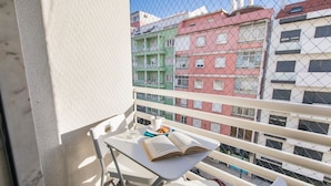 Un balcón con una mesa y una silla blancos, y un libro.