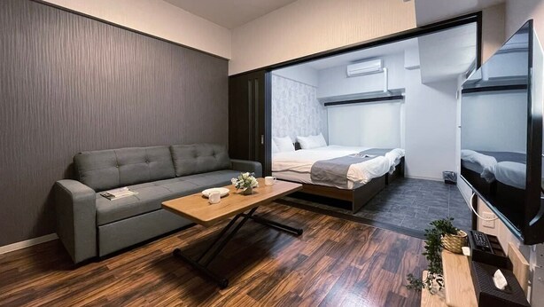 Ein modernes Hotelzimmer mit einer Couch, einem Bett, einem Fernseher und einem Holztisch.