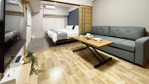 Una habitación de hotel compacta con cama, sofá, televisión y mesa de madera.