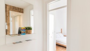 A modern bedroom with a wooden floor, a white bed, and a small window. - Historial Apartment Santos IV (Lisboa)