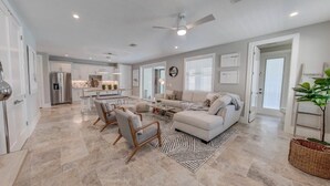 A spacious living area with a large sectional sofa, a coffee table, and a dining table with chairs.