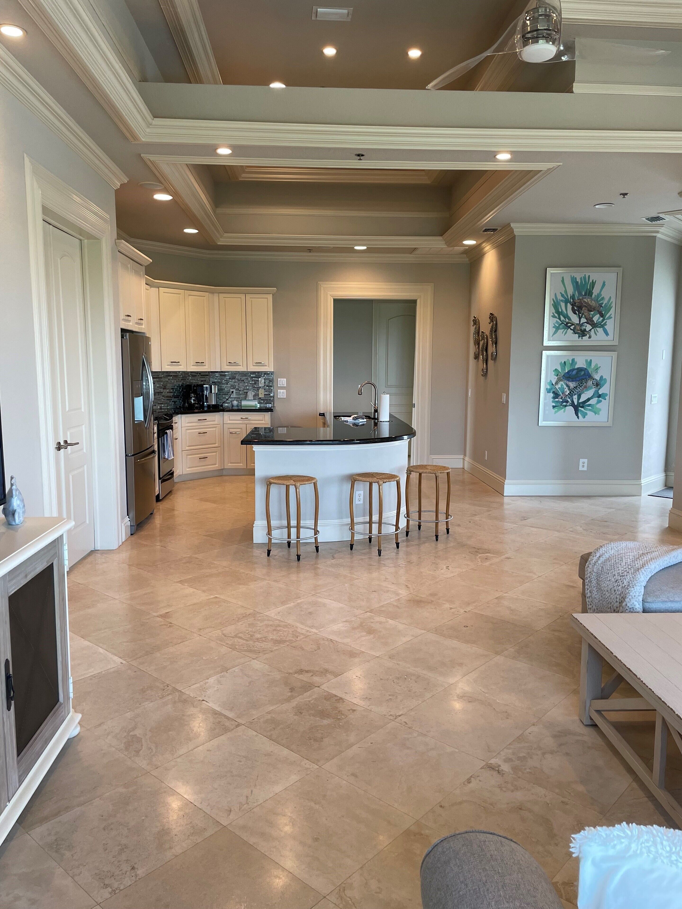 A spacious kitchen with a central island, recessed lighting, and a tiled floor.